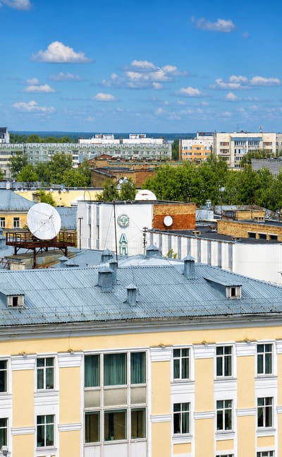 Rooftop view of Syktyvkar with a white golden-domed cathedral among Soviet-era apartment blocks.