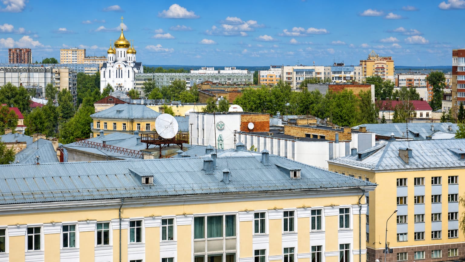 Rooftop view of Syktyvkar with a white golden-domed cathedral among Soviet-era apartment blocks.