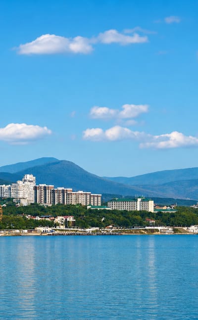 Gelendzhik's resort skyline along its bay, backed by the Markotkh mountains under a clear blue sky.
