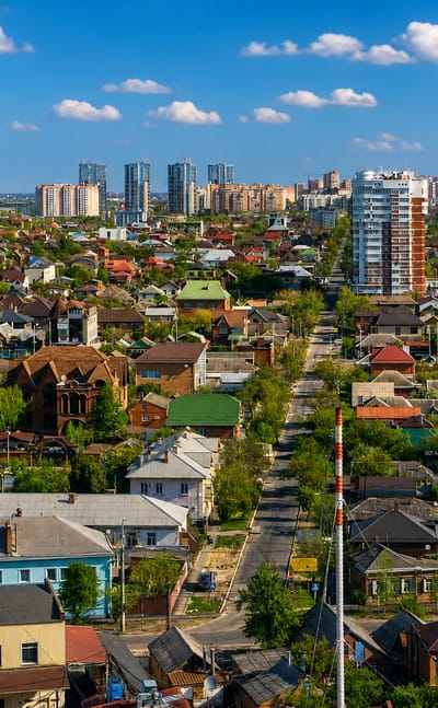 Krasnodar's residential districts with red-tiled roofs, tree-lined avenues and distant high-rise towers.