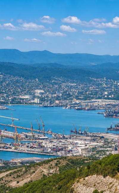 Novorossiysk's port cranes line Tsemes Bay, ringed by the wooded Caucasus foothills.