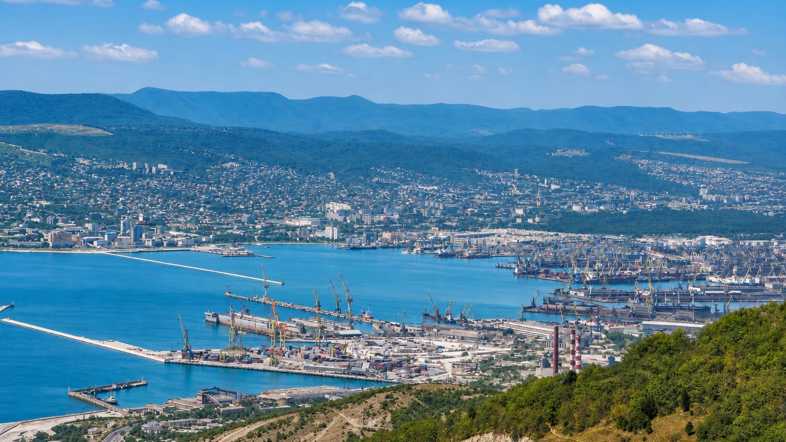 Novorossiysk's port cranes line Tsemes Bay, ringed by the wooded Caucasus foothills.