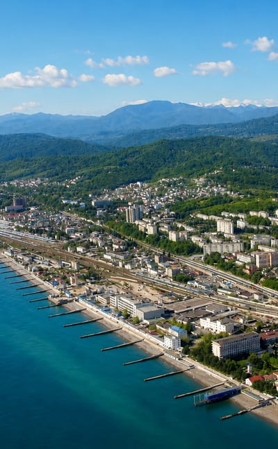 Aerial view of Sochi on the Black Sea coast with the snow-capped Caucasus mountains behind.