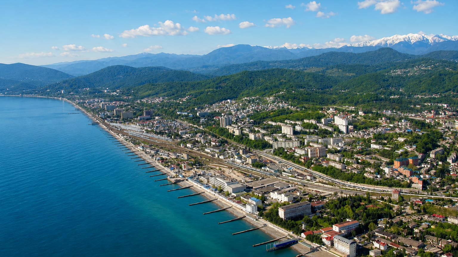 Aerial view of Sochi on the Black Sea coast with the snow-capped Caucasus mountains behind.