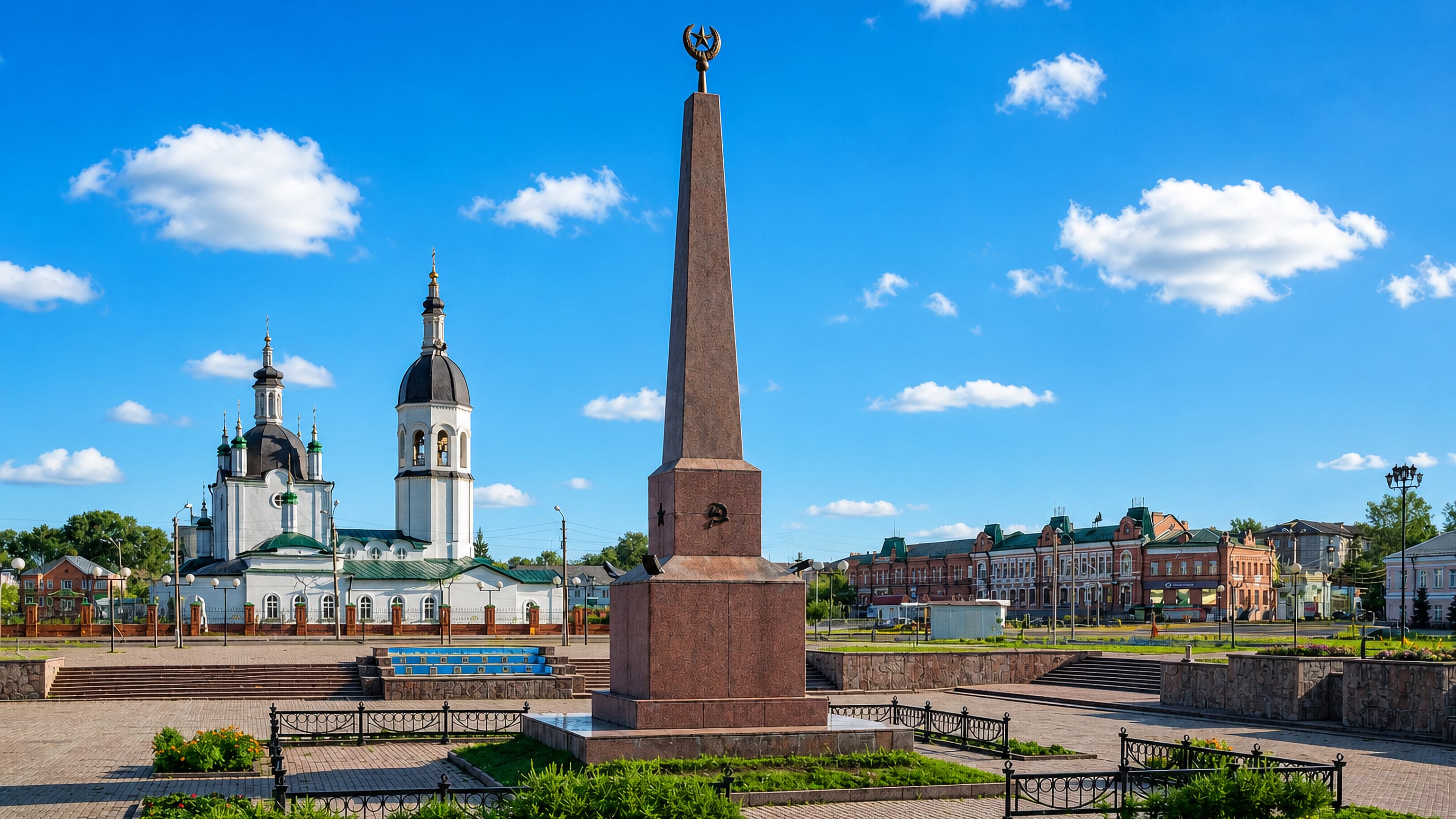 Central square in Kansk, Russia, with a granite obelisk, white Orthodox church and old merchant houses