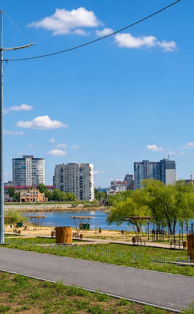 A riverside park with exercise equipment and apartment blocks across the water in Kurgan, Russia.