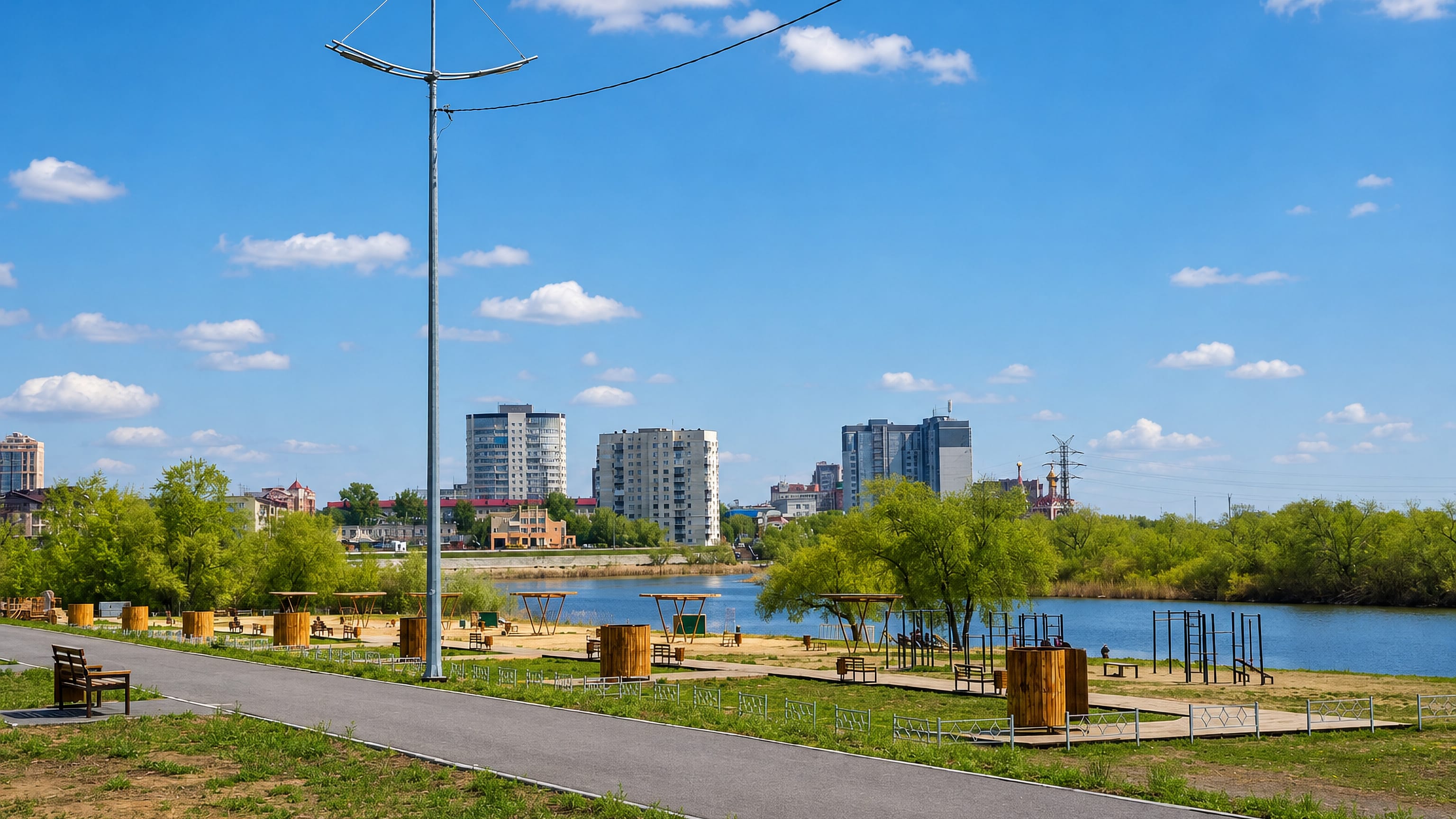 A riverside park with exercise equipment and apartment blocks across the water in Kurgan, Russia.