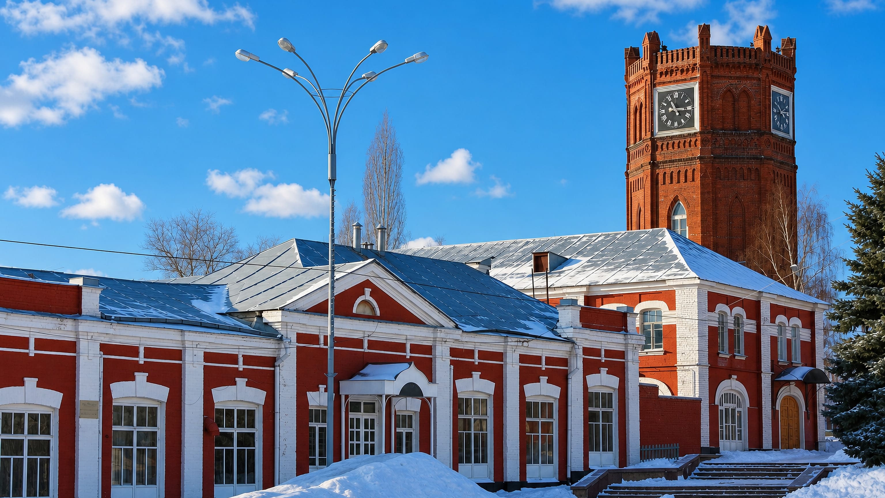 Snow-covered square in Yelets, Russia, with a red-brick civic building and the historic clock-topped brick tower.