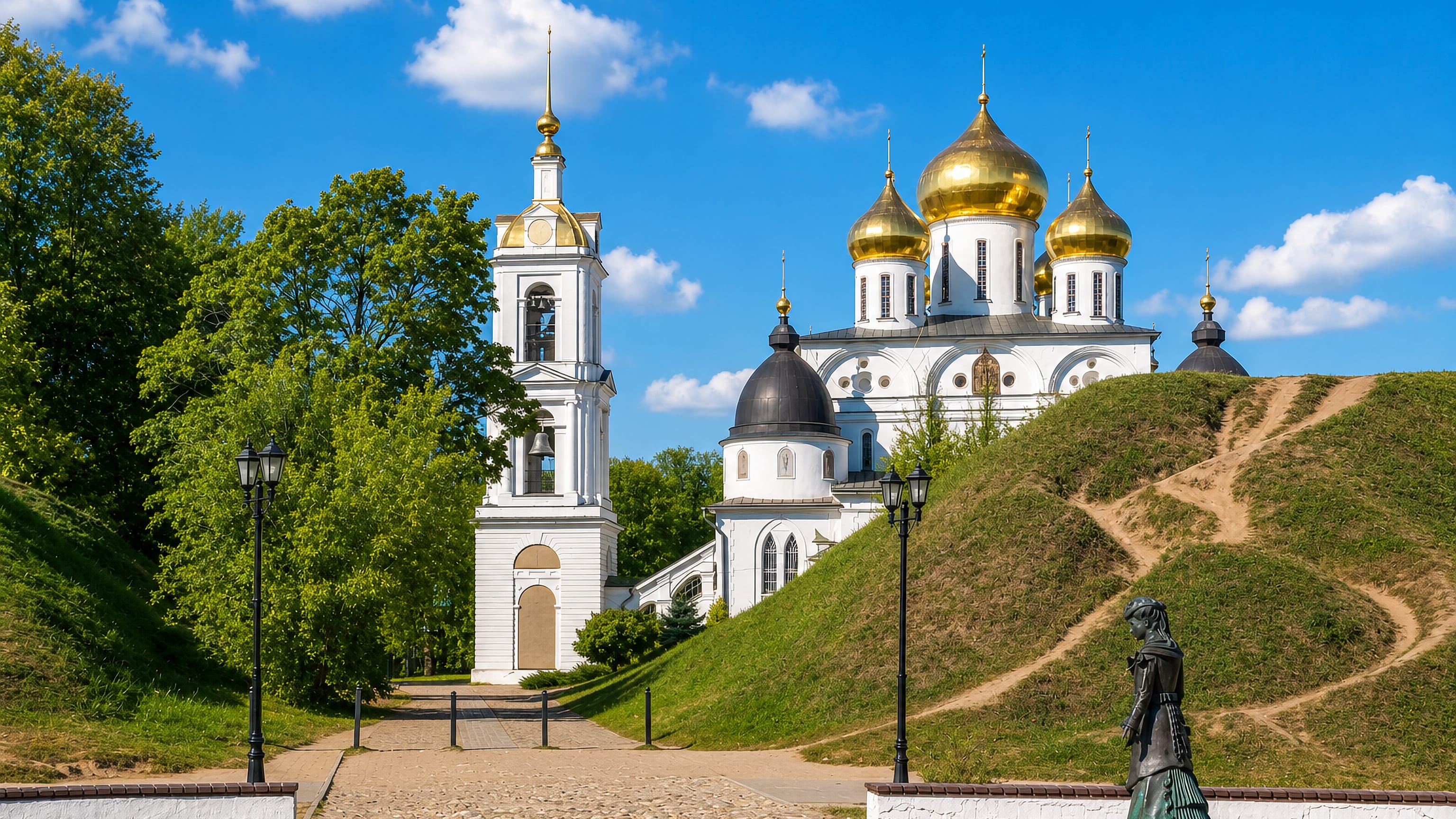 Gold-domed Assumption Cathedral and its bell tower inside the earthen ramparts of the Dmitrov Kremlin.