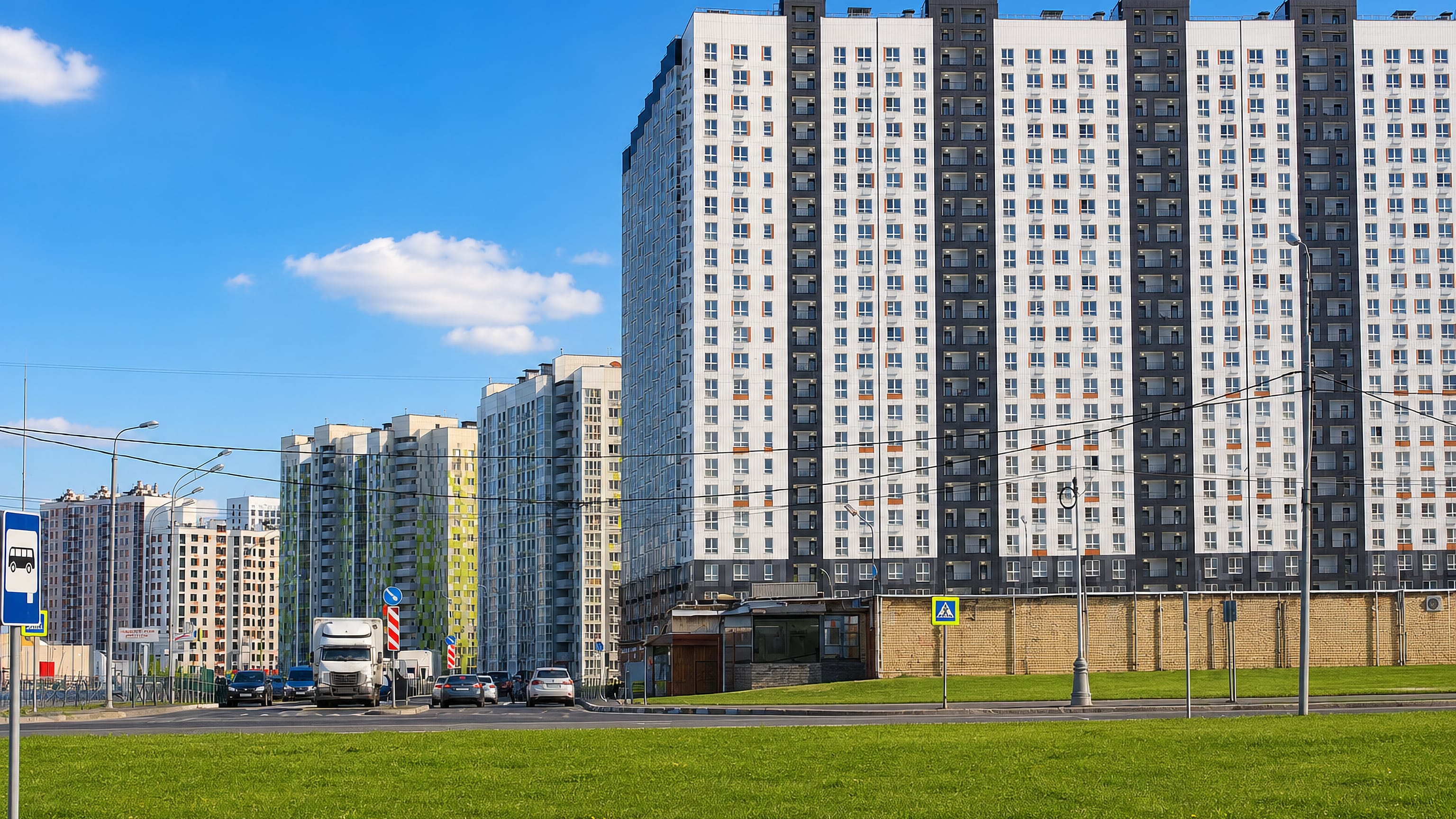 New high-rise apartment blocks lining a wide road in Lyubertsy, a Moscow suburb, under clear blue sky.