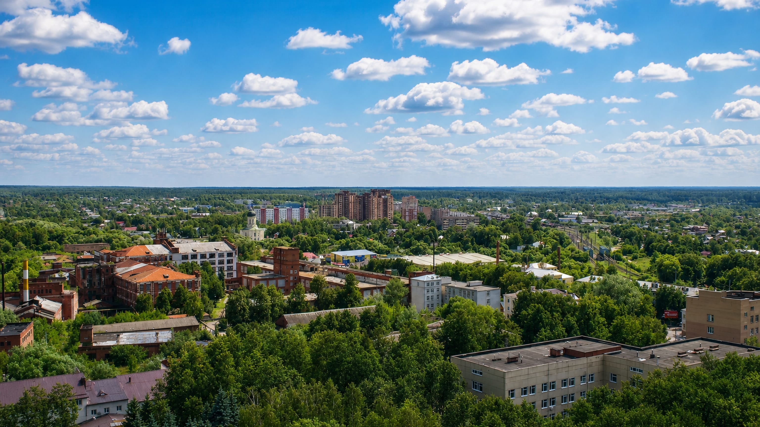 Aerial view over Naro-Fominsk, Russia, with red-brick mill buildings, apartment blocks and surrounding forest.