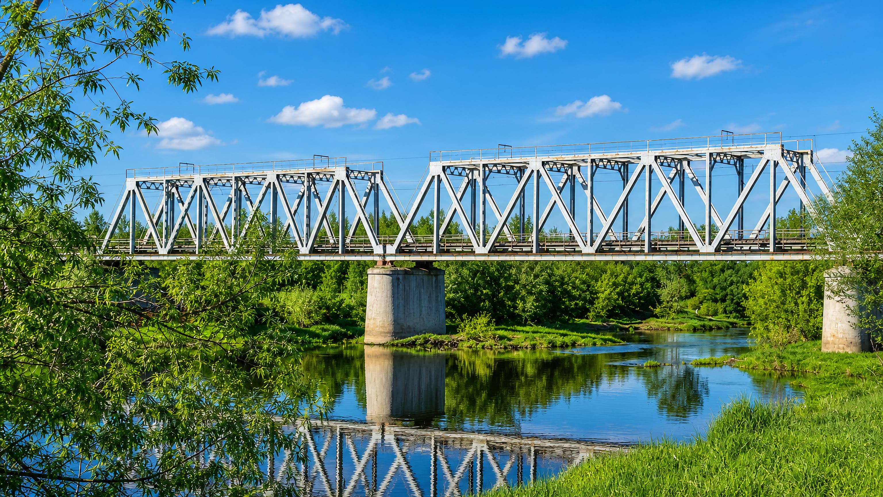 Steel railway truss bridge crossing a calm river among summer greenery near Pavlovskiy Posad, Russia