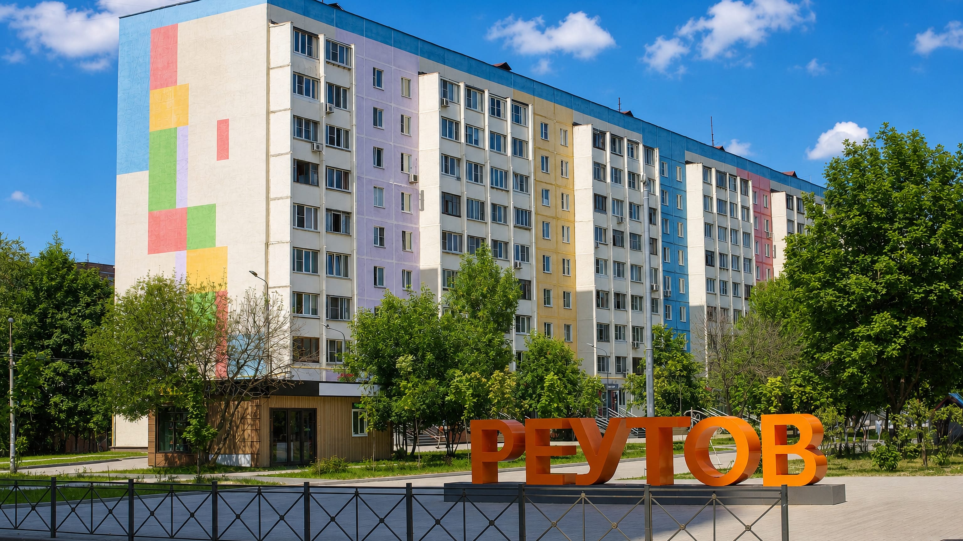 Orange REUTOV lettering beside a colourfully painted apartment block in Reutov, Moscow Oblast