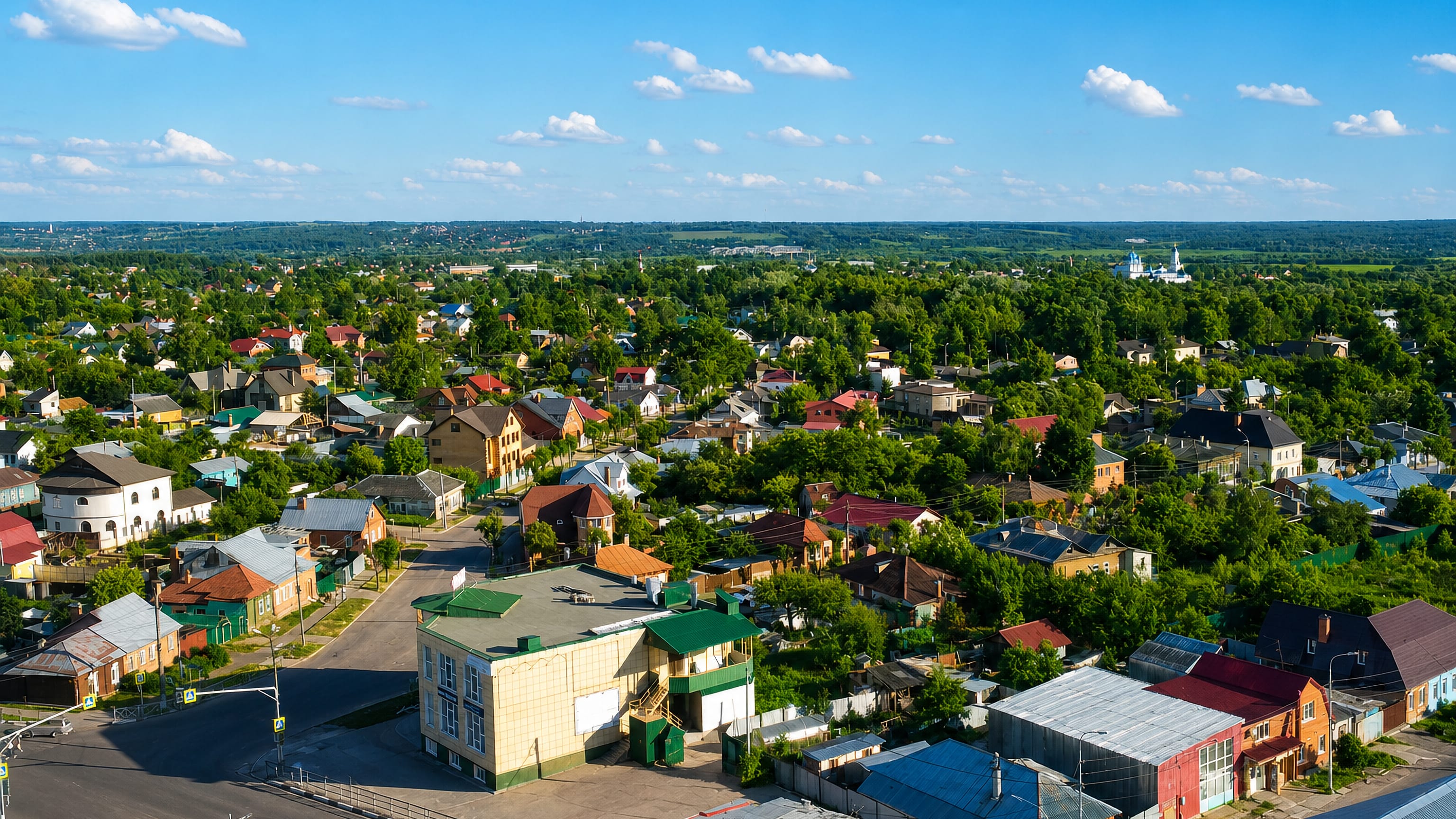 Aerial view of Serpukhov, Russia, with wooden houses, leafy streets and a white monastery on the horizon