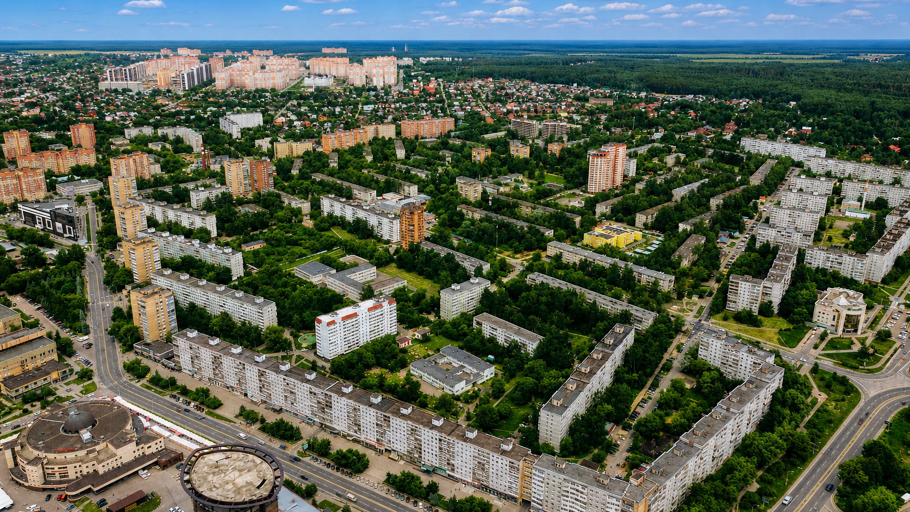 Aerial over Shchyolkovo, Russia, showing Soviet-era apartment blocks, green courtyards and forest beyond