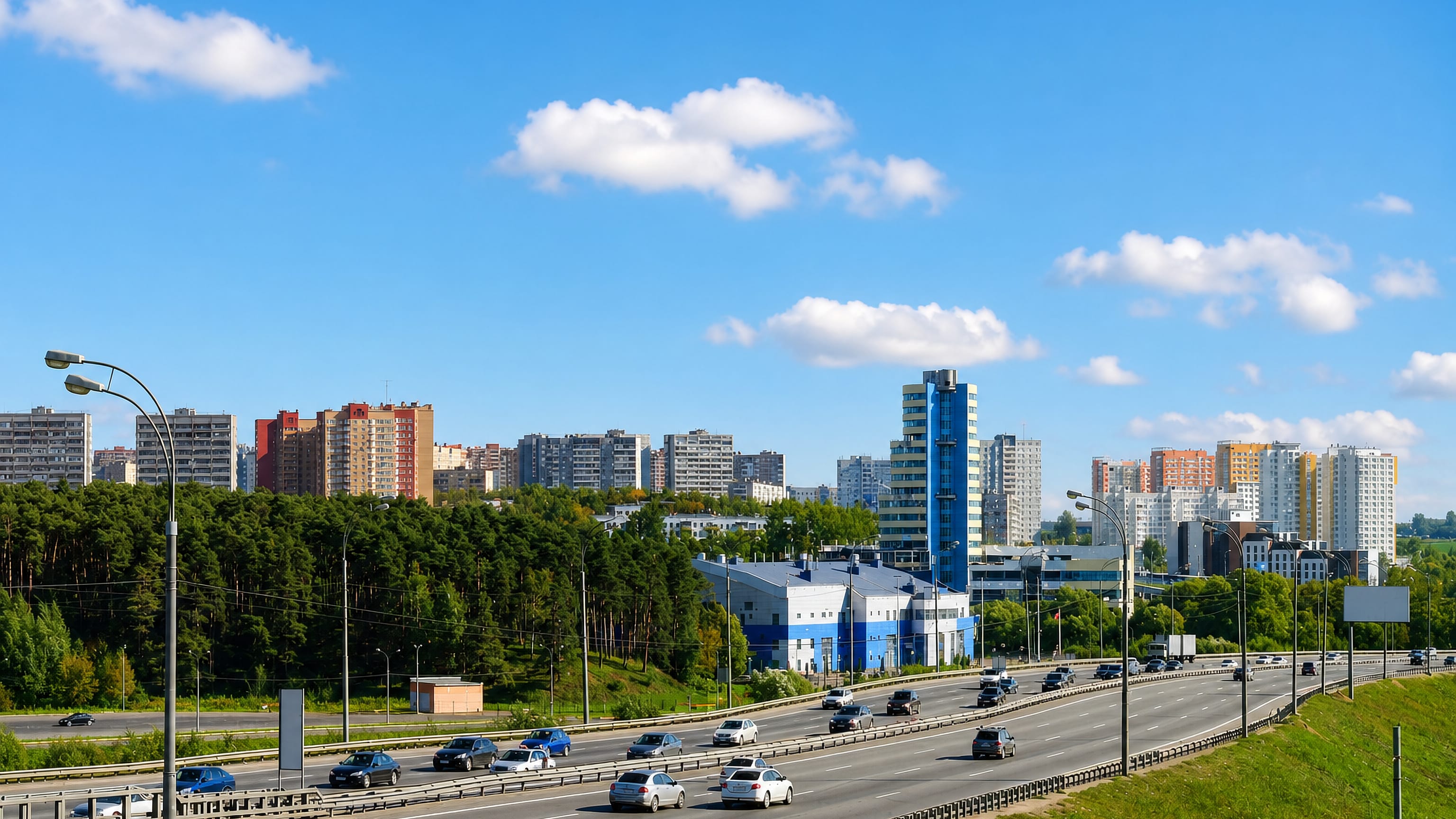 Highway traffic passing high-rise apartment blocks and woodland in Vidnoye, Moscow Oblast.