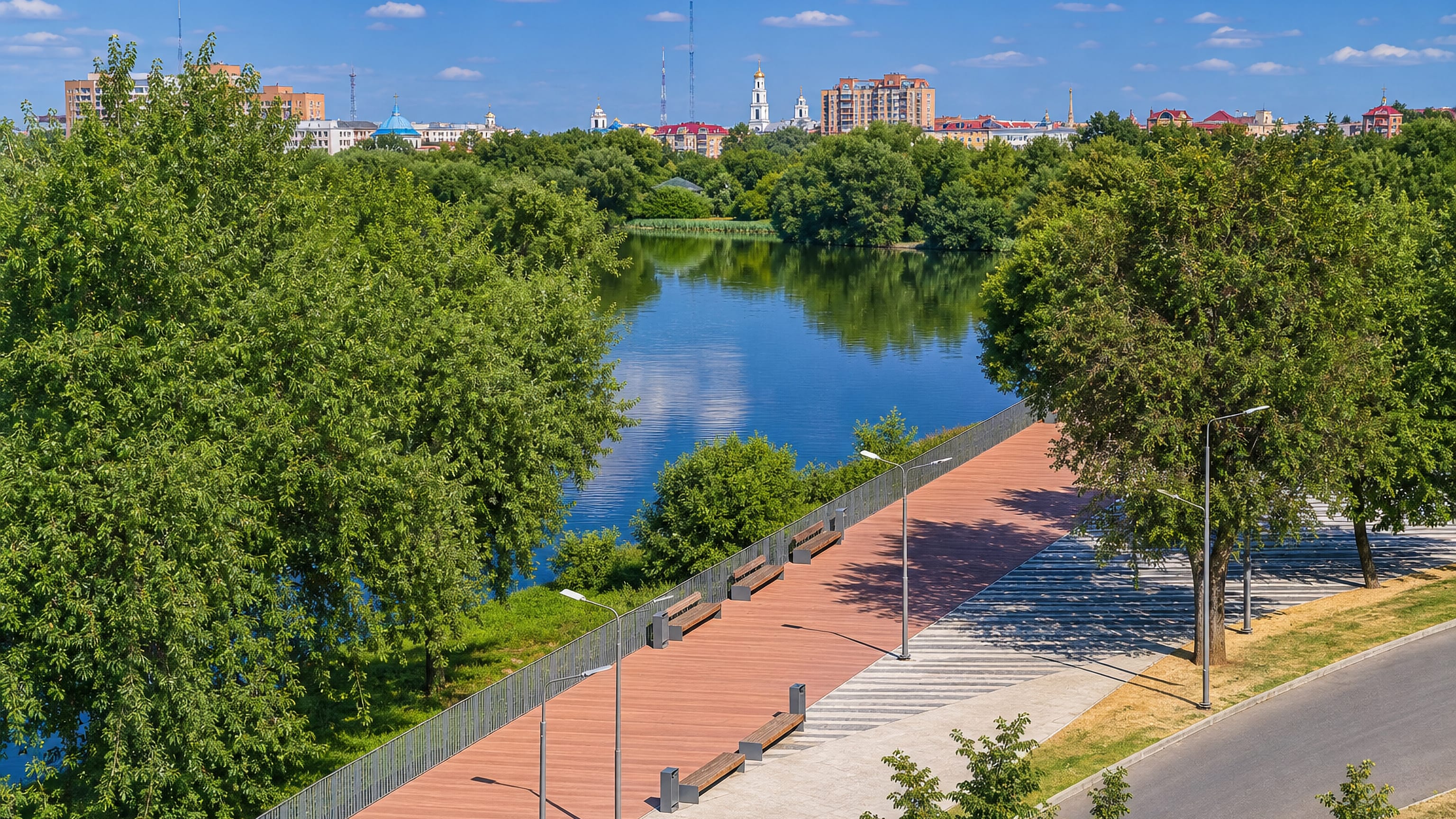 Riverside promenade with benches in Zhukovsky, church domes and apartment blocks on the far skyline.