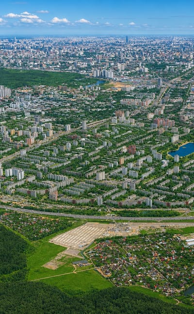 Aerial view of the residential blocks, ponds and greenery of Izmaylovo district with the Moscow skyline on the horizon.