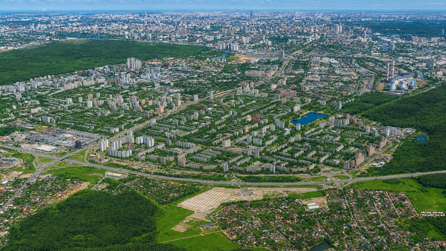 Aerial view of the residential blocks, ponds and greenery of Izmaylovo district with the Moscow skyline on the horizon.