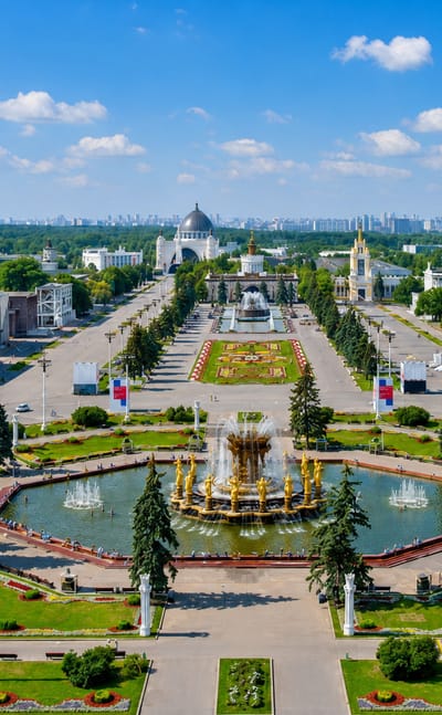 Aerial view of VDNKh park in Ostankinsky, Moscow, with the Stone Flower Fountain, pavilions and city skyline beyond.