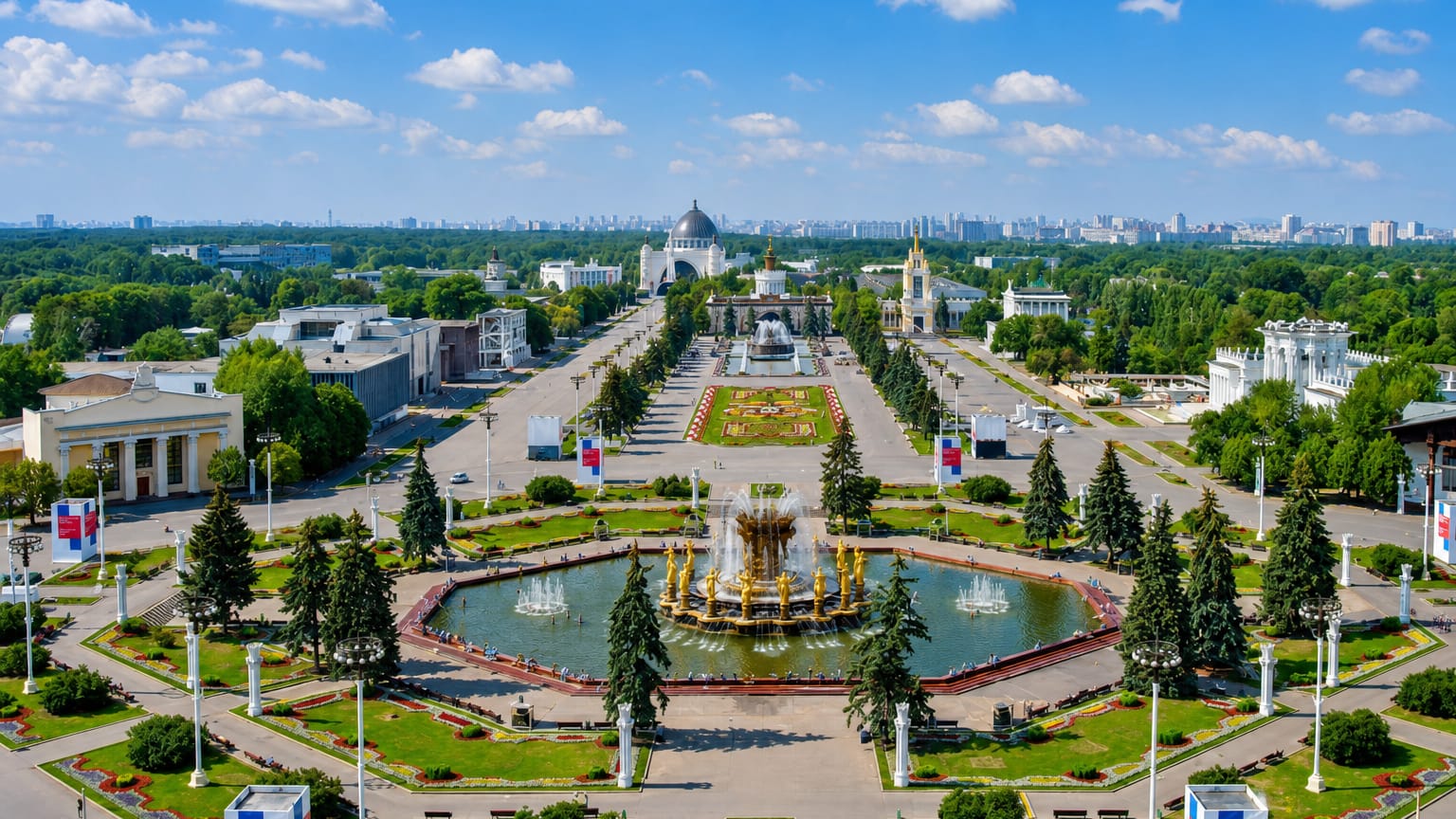 Aerial view of VDNKh park in Ostankinsky, Moscow, with the Stone Flower Fountain, pavilions and city skyline beyond.