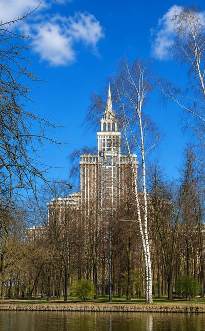 Stalin-era spired skyscraper rising above a pond and birch trees in the Sokol district of Moscow