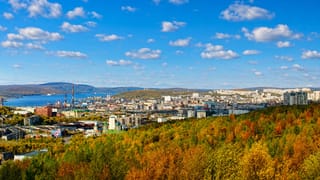 Murmansk spread over hills above the Kola Bay port, framed by golden autumn forest.