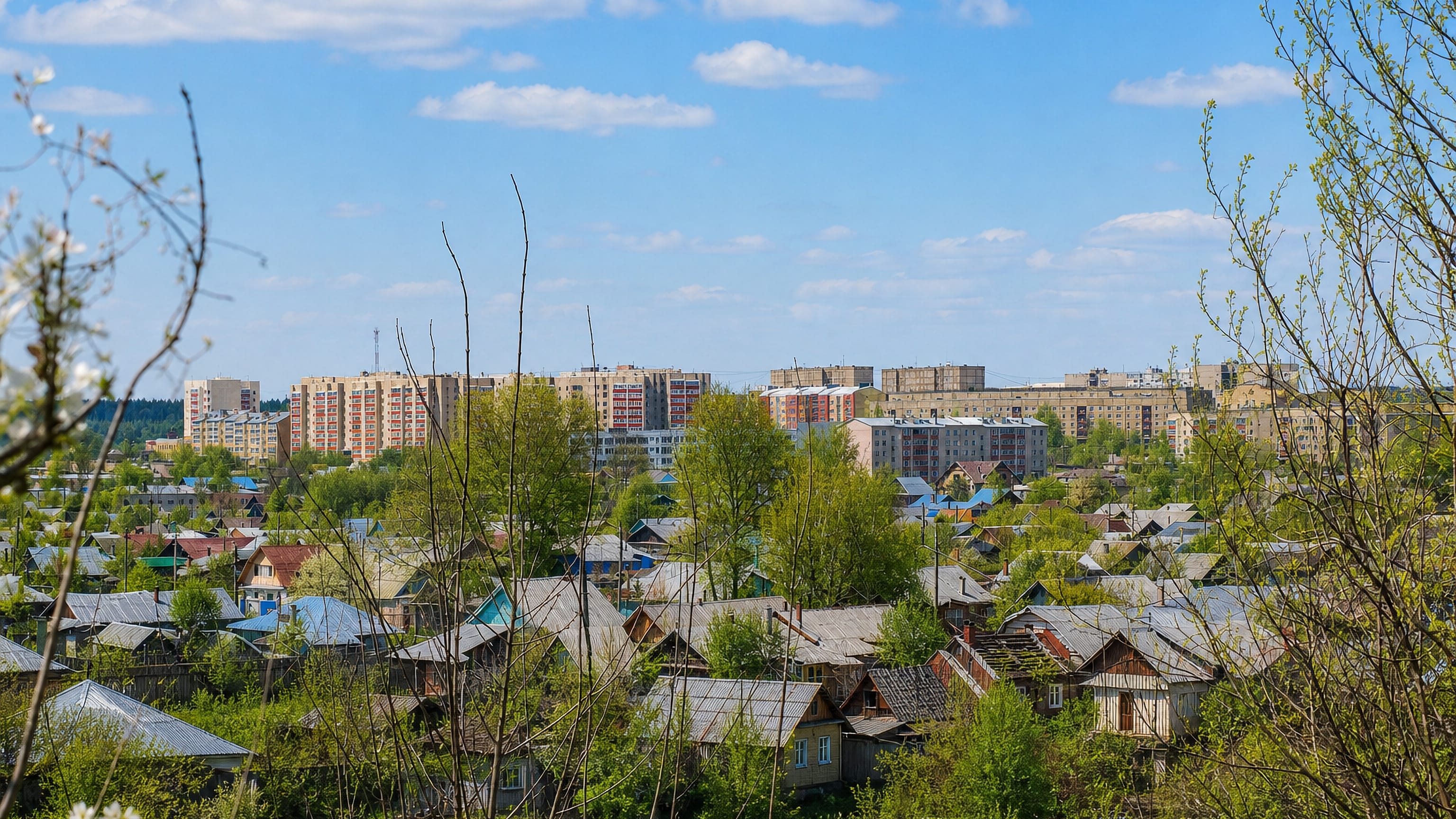 Wooden houses and Soviet-era apartment blocks spread across Arzamas, Russia, on a bright spring day.
