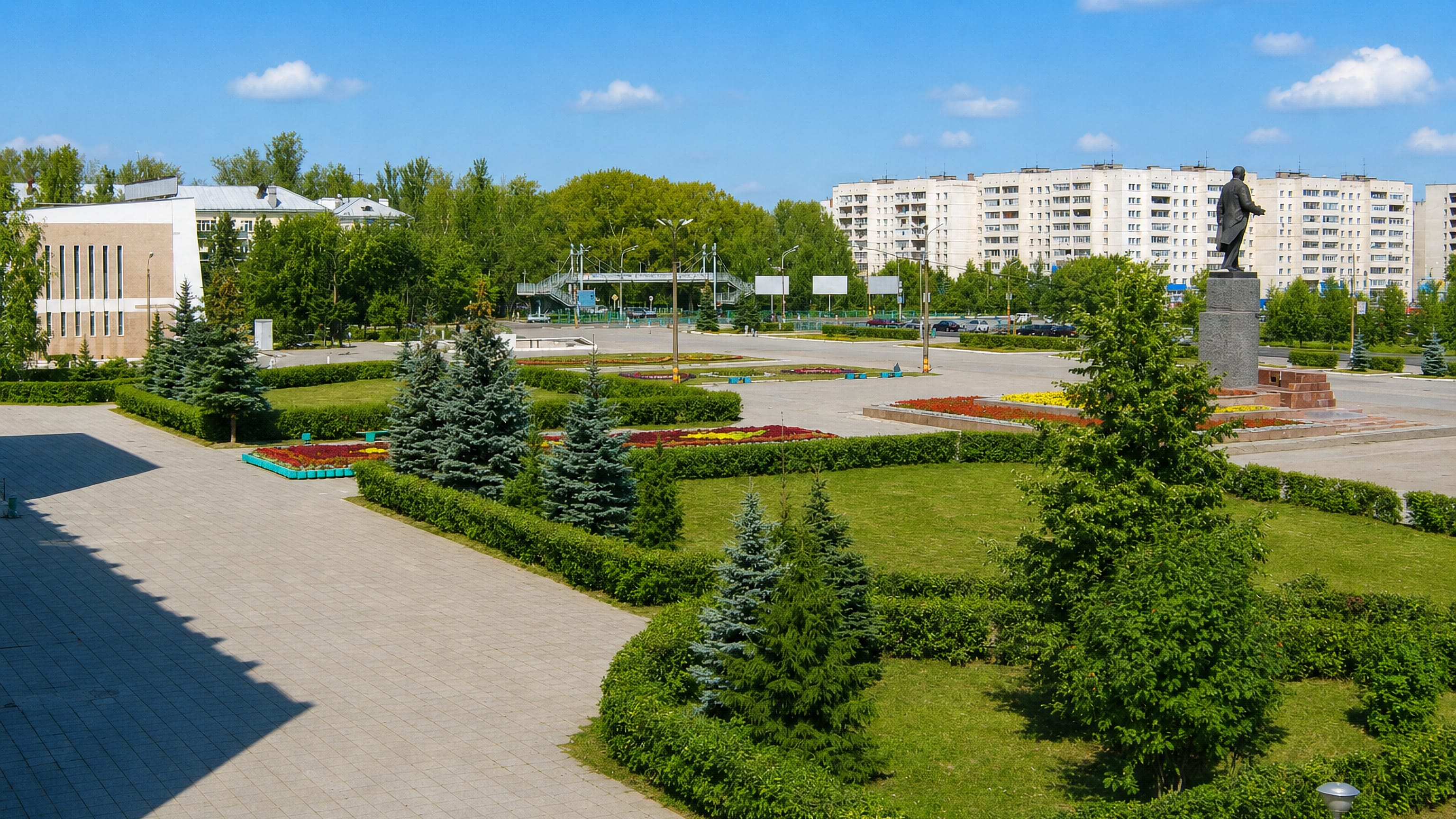 Landscaped central square with a Lenin statue and Soviet-era apartment blocks in Kstovo, Russia.