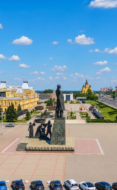 Kanavinsky District plaza in Nizhny Novgorod with a monument, historic fair building and the golden-domed Alexander Nevsky Cathedral by the river
