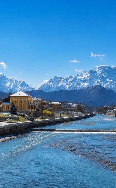 River flowing through a snow-capped mountain town representing Vladikavkaz, Russia