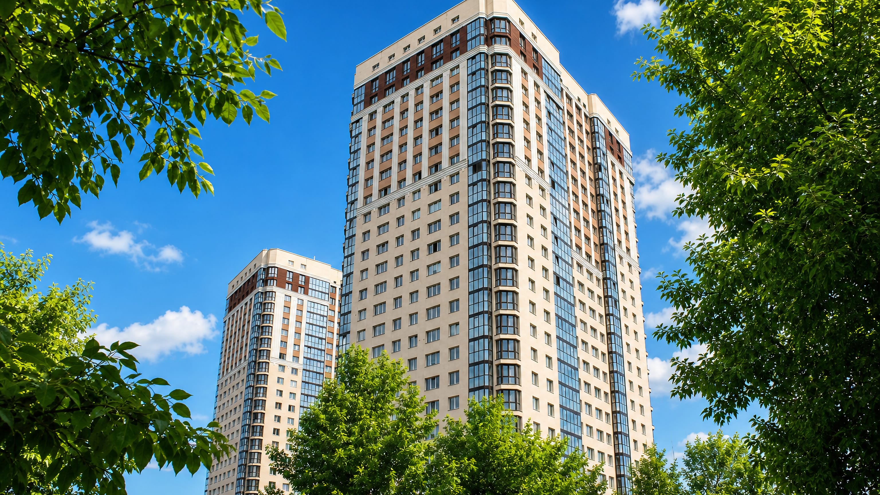 Modern high-rise residential towers rising above summer trees in Kirovsky City District, Novosibirsk.