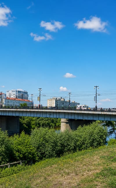Road bridge carrying traffic over the Om River with Omsk's riverfront buildings behind.