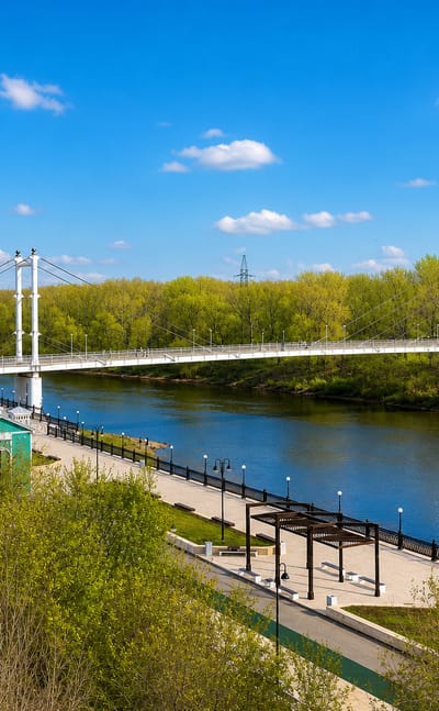 Orenburg's cable-stayed pedestrian bridge over the Ural River with a landscaped riverside embankment.