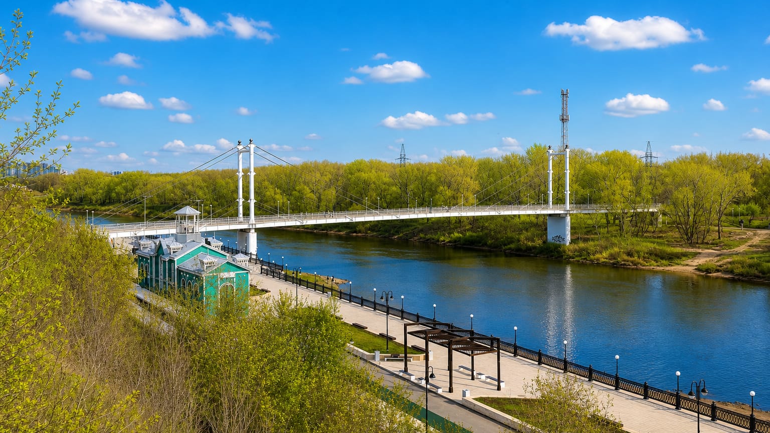 Orenburg's cable-stayed pedestrian bridge over the Ural River with a landscaped riverside embankment.
