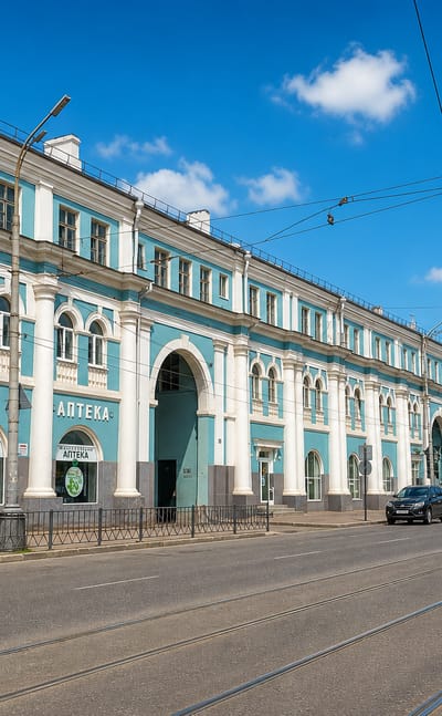 Long teal classical trading row with pharmacy signs along a tram-lined street in Oryol.