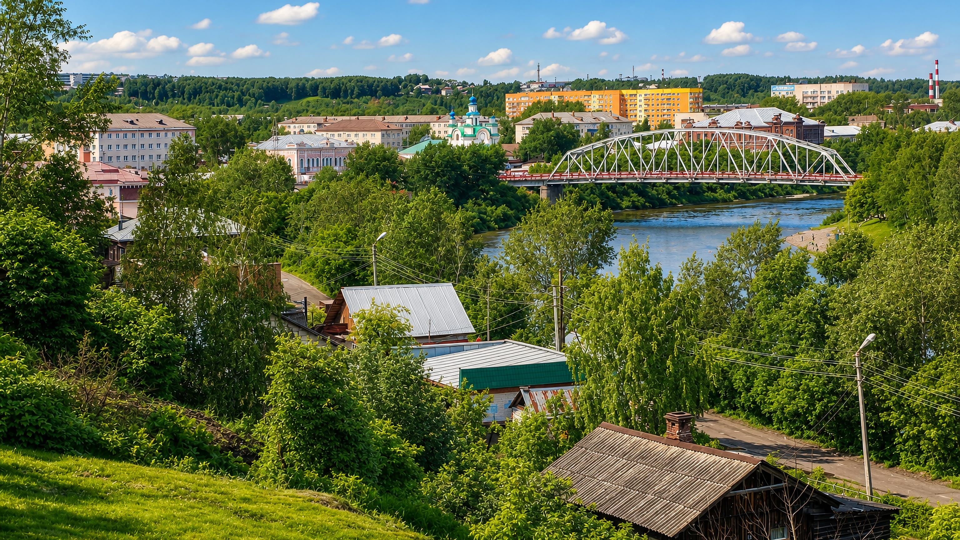Kungur, Russia, seen across the Sylva River with a steel truss bridge, blue-domed church and wooden houses