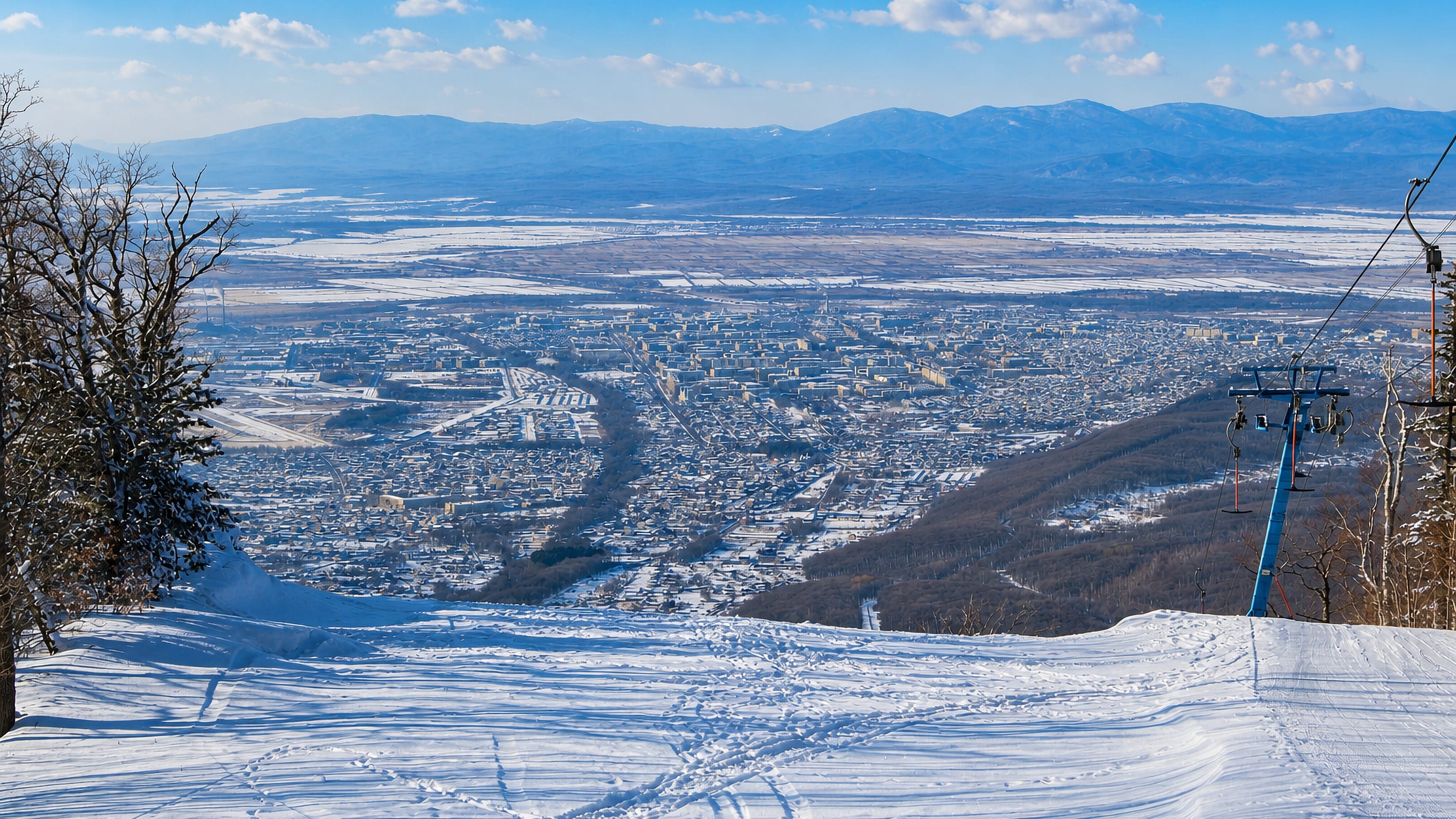 Snow-covered ski slope above Arsenyev, Russia, looking down over the town and surrounding mountains