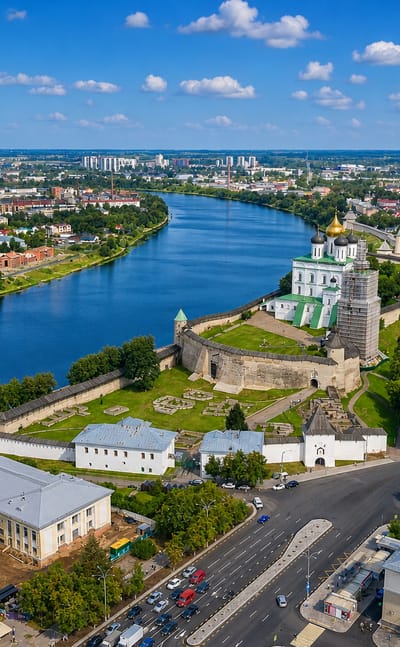 Aerial view of the Pskov Kremlin's white walls and gold-domed cathedral at the river confluence.
