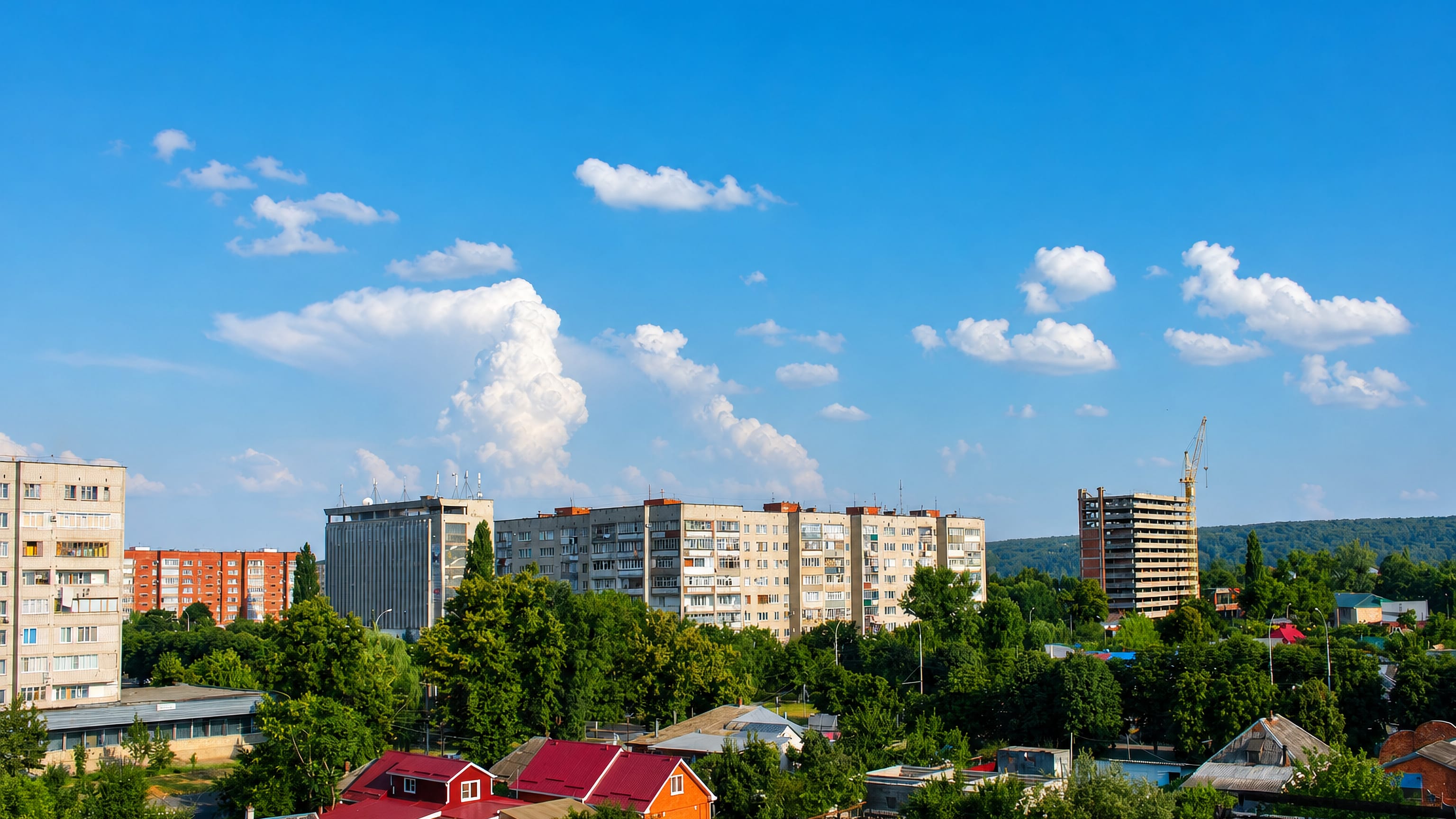 Soviet-era apartment blocks and red-roofed houses among summer trees in Maykop, Republic of Adygea