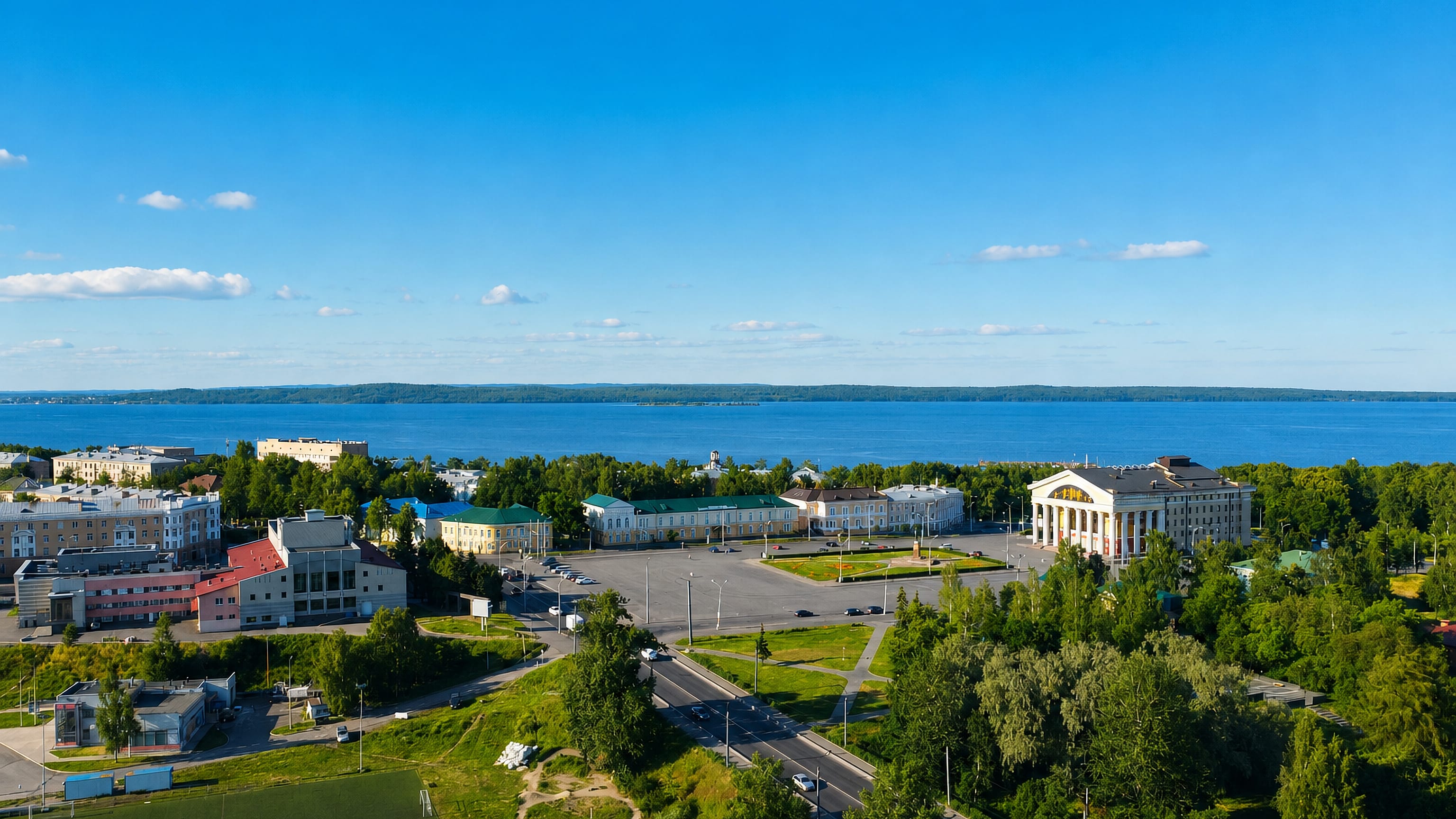Aerial view of Petrozavodsk with a columned building and Lake Onega stretching to the horizon.