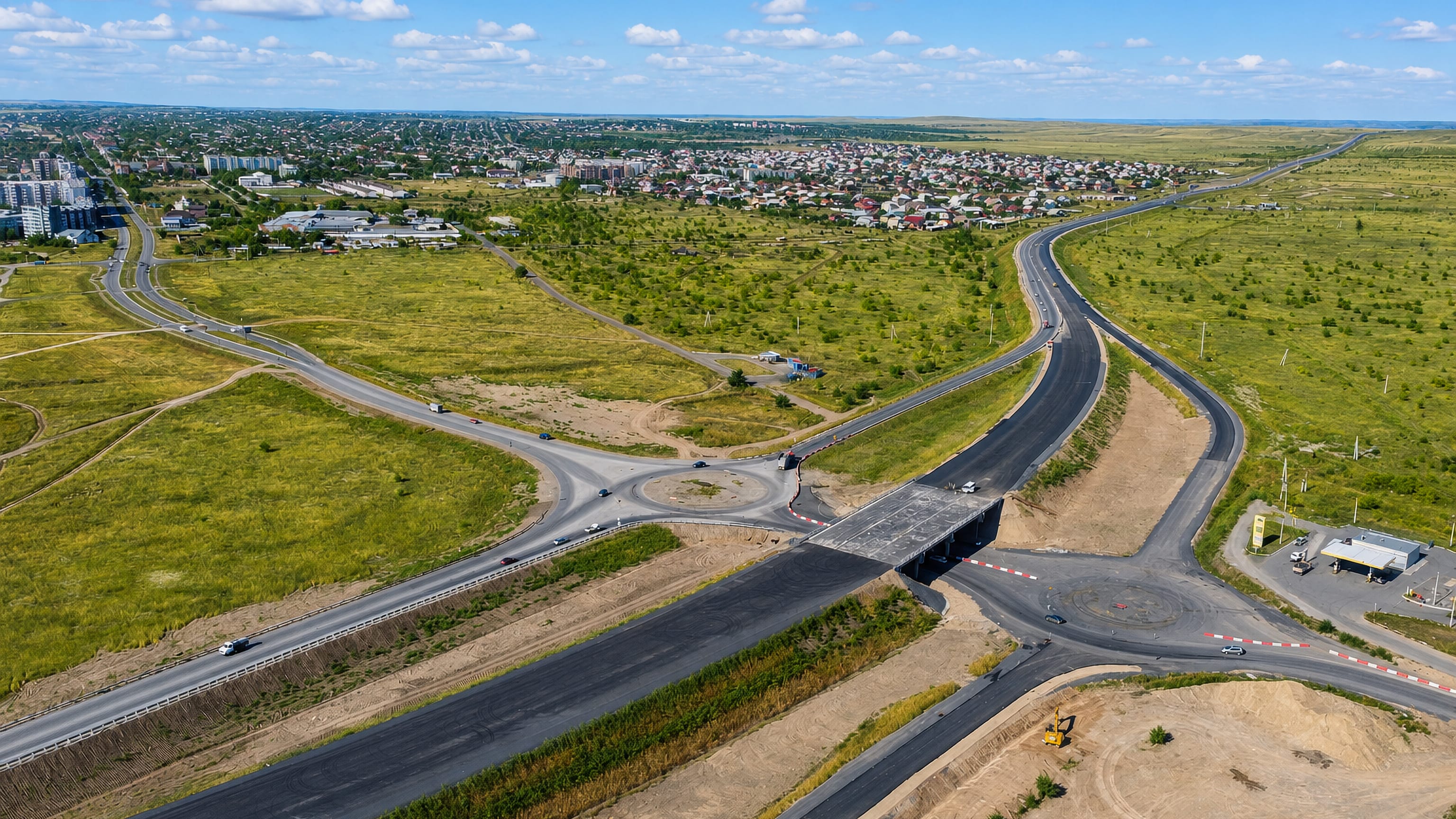 Aerial view of Chernogorsk spread across the Khakassian steppe beyond a new highway interchange.