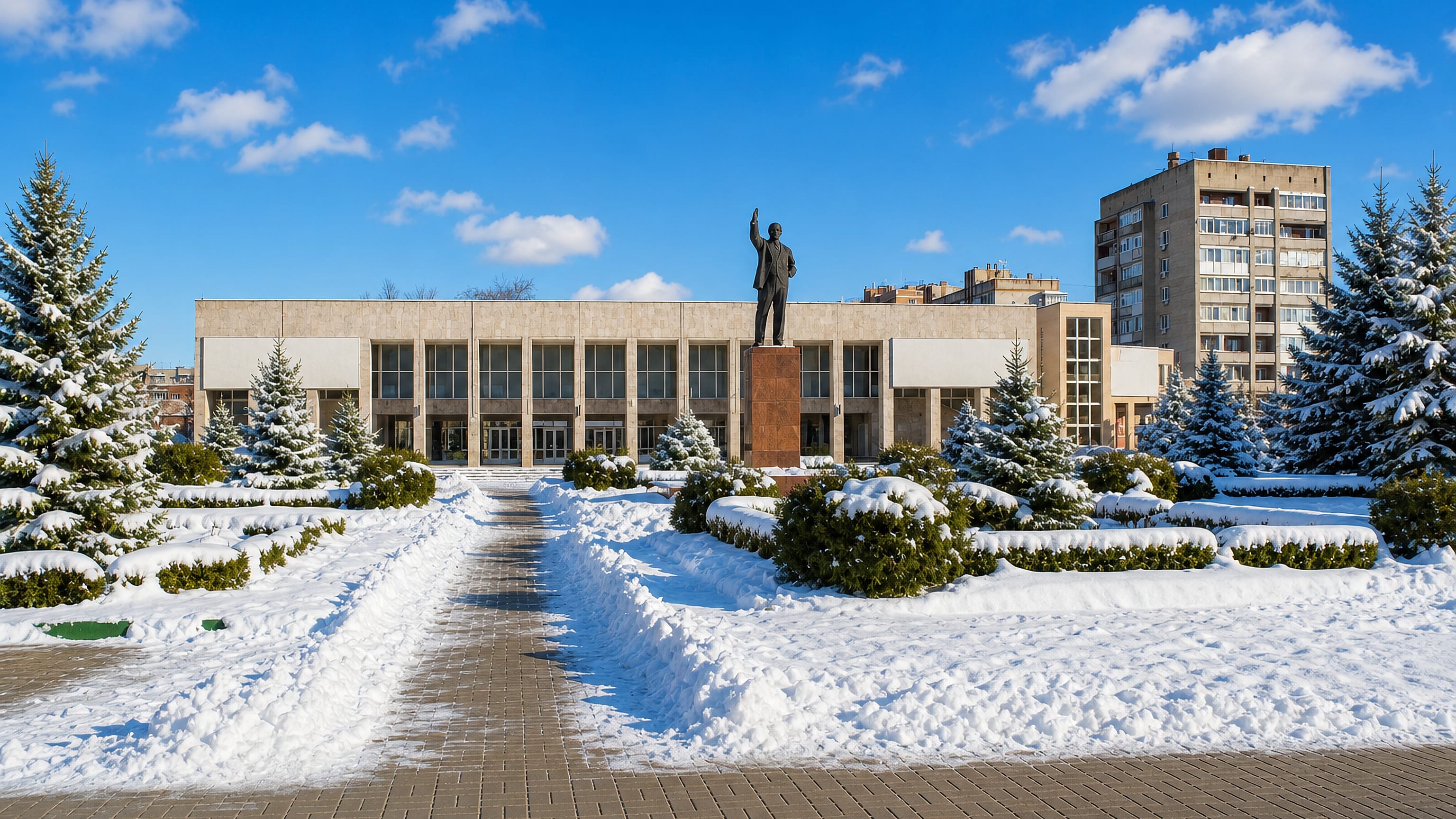Snow-covered central square in Bataysk, Russia, with a Lenin statue before a modernist house of culture.