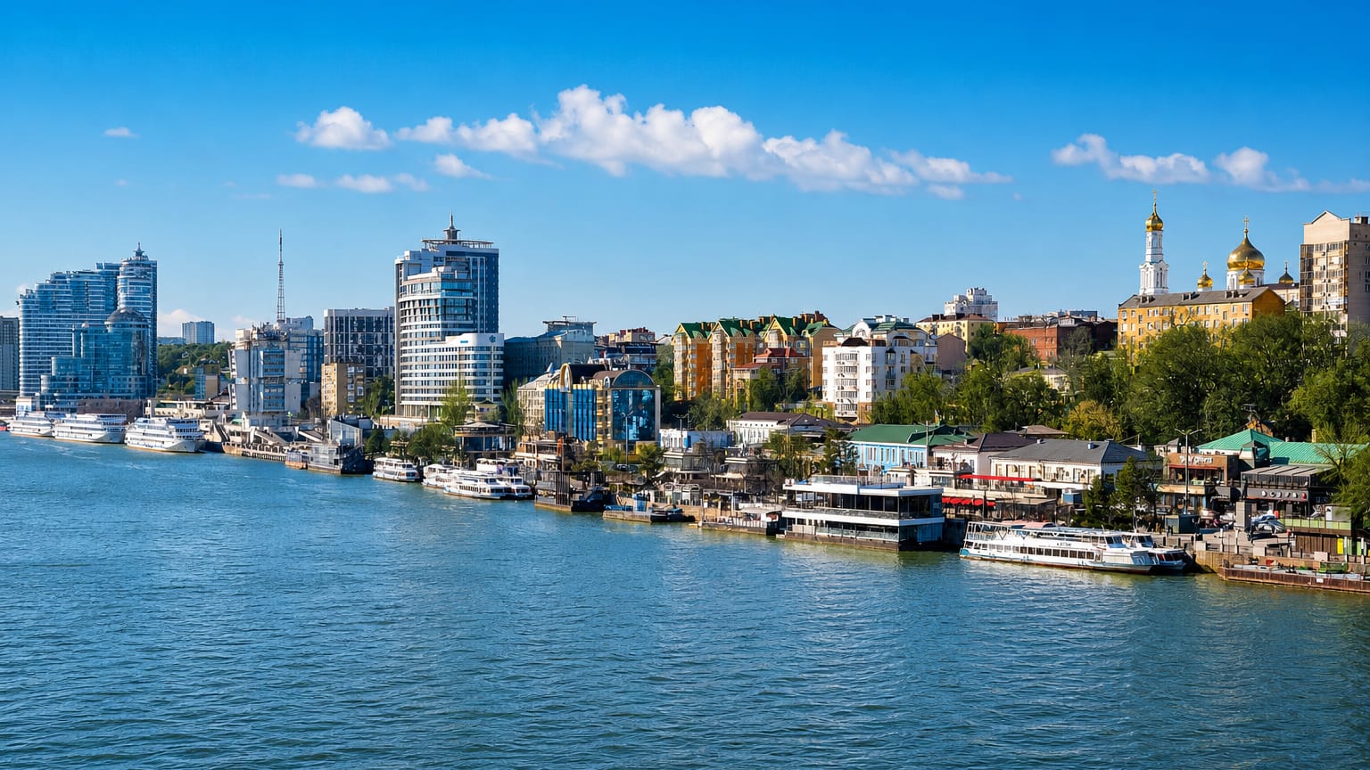 Rostov-on-Don Don River embankment with moored river boats, a golden-domed cathedral and mid-rise buildings