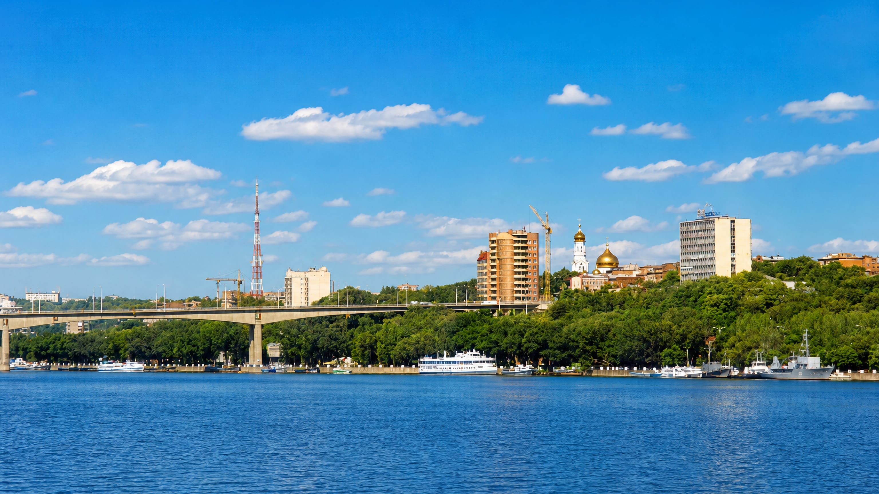 Kirovsky District, Rostov-on-Don, across the Don River: golden-domed cathedral, wooded bluff, quays and a road bridge.