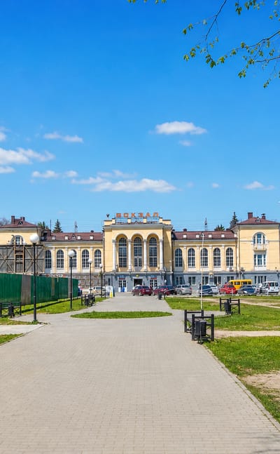 Yellow classical railway station and park promenade in Taganrog on a sunny day.