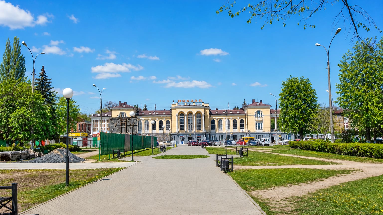 Yellow classical railway station and park promenade in Taganrog on a sunny day.