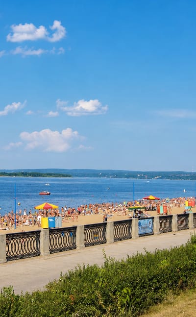 Samara's Volga River embankment and its crowded city beach on a bright summer day.