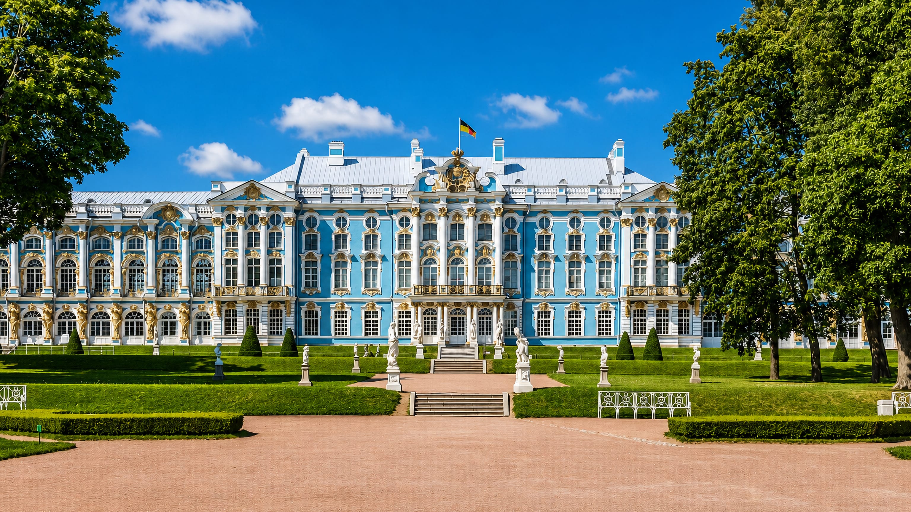 The blue-and-white Baroque Catherine Palace and its formal gardens under a summer sky in Pushkin, Russia.