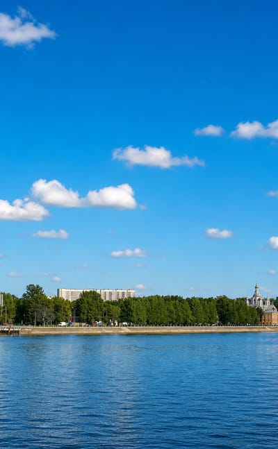 Waterfront across the Neva showing a tower block, an Orthodox church and an industrial chimney in Krasnogvardeysky, Saint Petersburg.